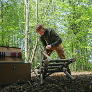 Elev står og arbejder med knive i naturen
