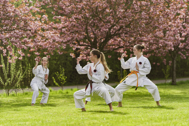 Kvinder udøver karate foran kirsebærtræer på Bosei